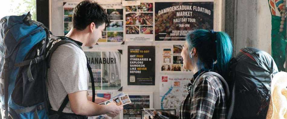 Students with backpacks checking a travel notice board